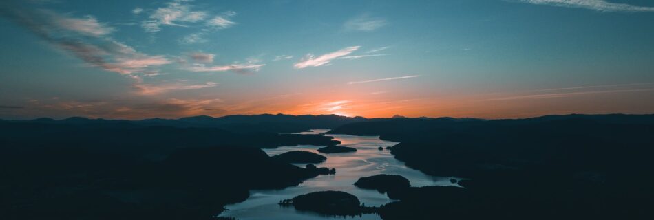 aerial photography of water beside forest during golden hour